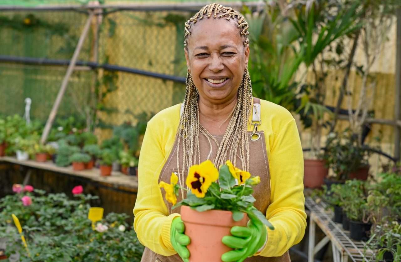 happy gardener with potted flower in greenhouse